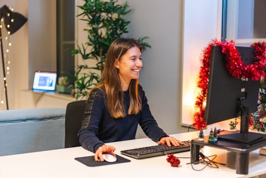 Woman working happily in a festive office setting during the holiday season.