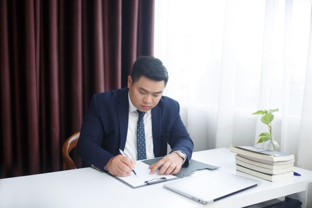 Lawyer Salaries by State: California vs. Texas vs. New York Asian businessman in a suit writing at his desk in an office environment, focusing on documents.