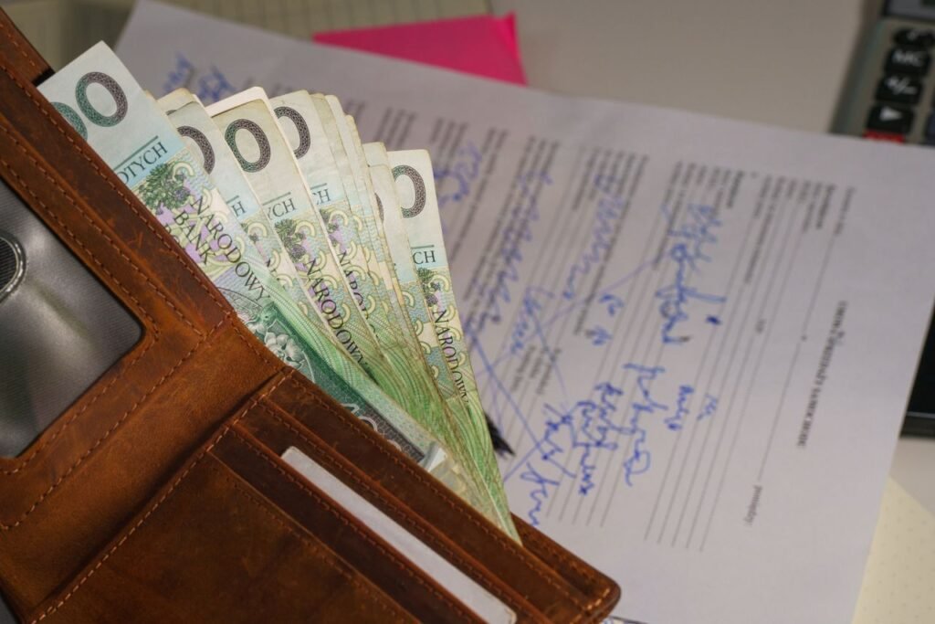 How to Negotiate Your Salary in the US: A Simple Guide Close-up of a wallet containing Polish Zloty with a signed document in the background, representing financial transactions.