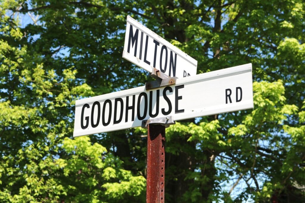 Street signs for Milton Rd and Goodhouse Rd with trees in the background.