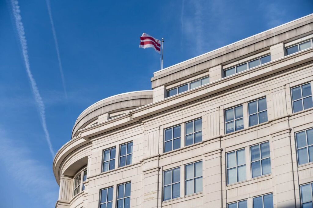 Government Jobs vs Private Sector: Which One Actually Wins? Exterior of a building in Washington DC with District of Columbia flag waving.