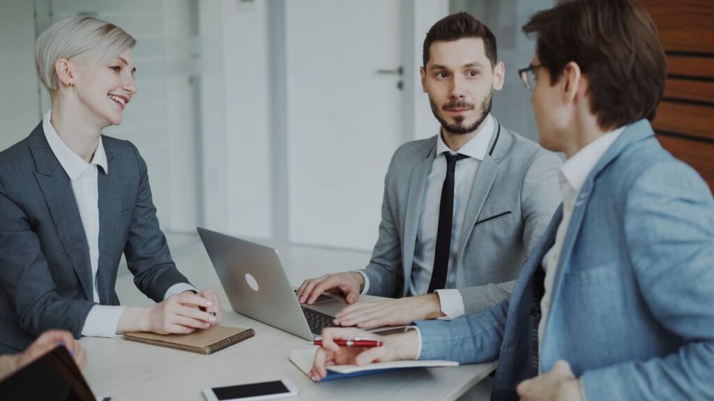 Top 10 Highest-Paying Jobs in the U.S. for 2026 Business professionals in a meeting with laptops and notebooks, discussing strategy.