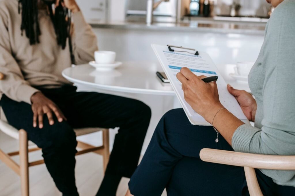 How to Prepare for a Job Interview in the US: A Step by Step Guide Crop unrecognizable female psychotherapist or interviewer asking questions and taking notes in clipboard during interview with black male