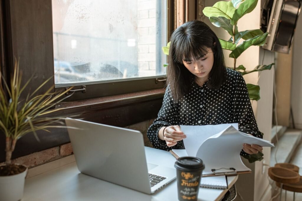 No College Degree? Here Are 5 Careers That Still Pay Well Asian businesswoman reviewing documents in a modern office setting with natural light.