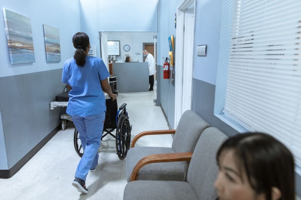 California Nurse Salaries by Experience: What RNs Actually Earn A nurse in scrubs pushes a wheelchair through a well-lit hospital corridor, attending to patient care.
