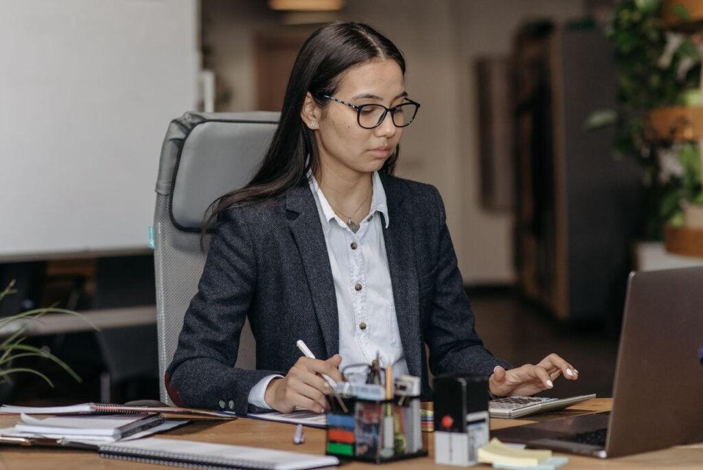 How Much Do U.S. Federal Employees Actually Make? A Simple Guide to the GS Pay Scale Young woman working with concentration at her laptop in a modern office setting, wearing eyeglasses.