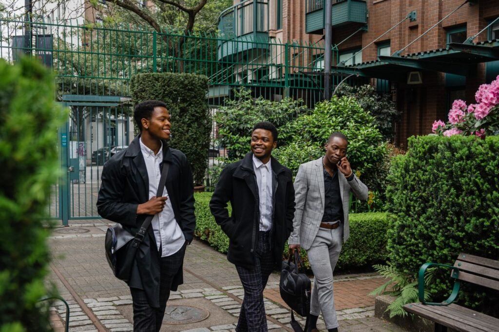 Three smiling businessmen walking outdoors in a garden area, dressed in business attire.