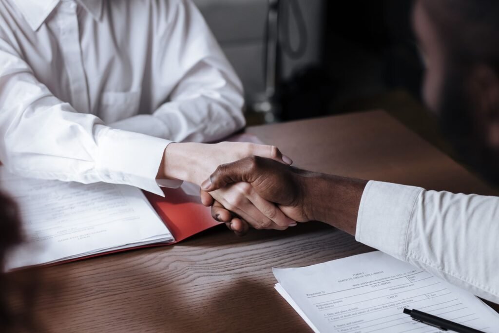 How to Write a Resume for the US Job Market: A Step by Step Guide Close-up of a diverse business handshake over documents, symbolizing agreement and collaboration.
